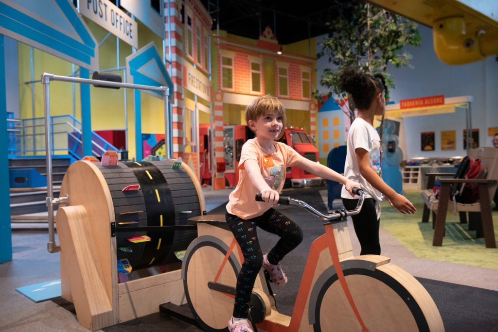Girl riding on play bike at Minnesota Children's Museum in st paul minnesota