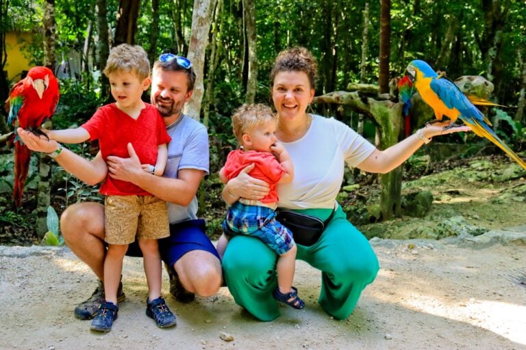 family with two boys holding parrots on vacation
