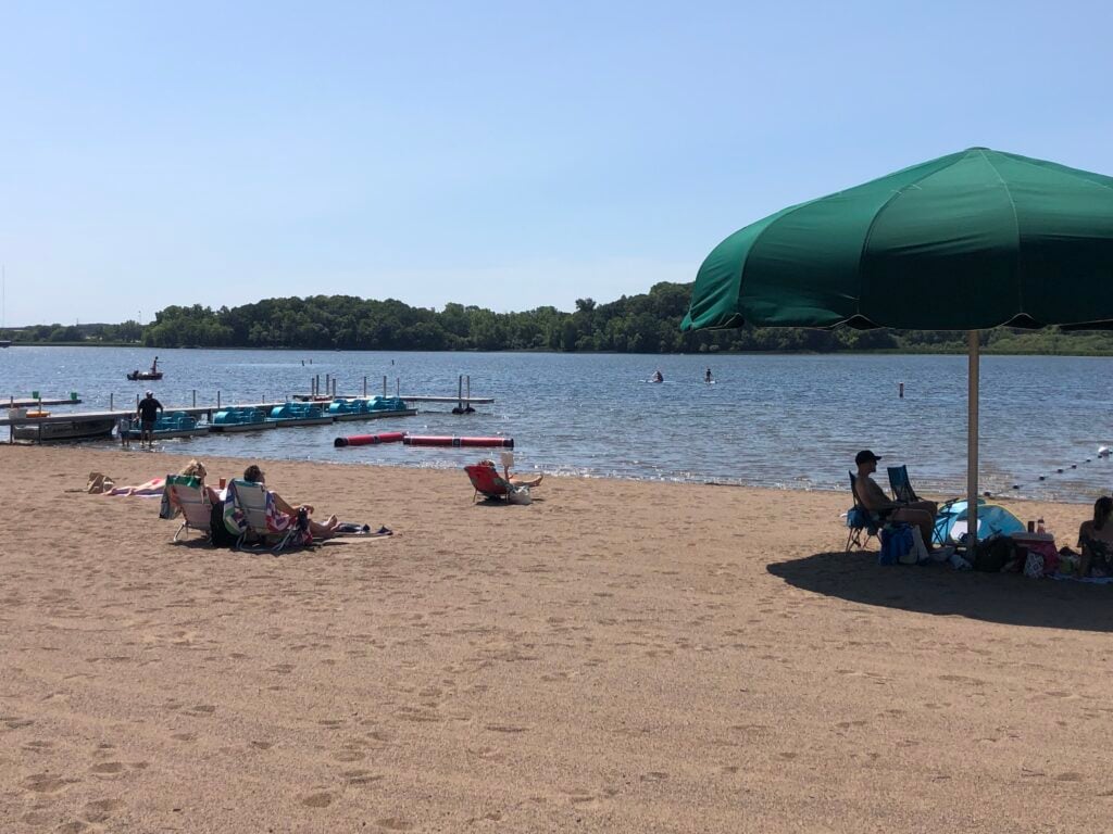 swimming beach at bryant lake park in eden prairie, mn with umbrellas and dock in the lake